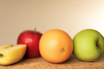 Oranges and apples on wooden table, close-up