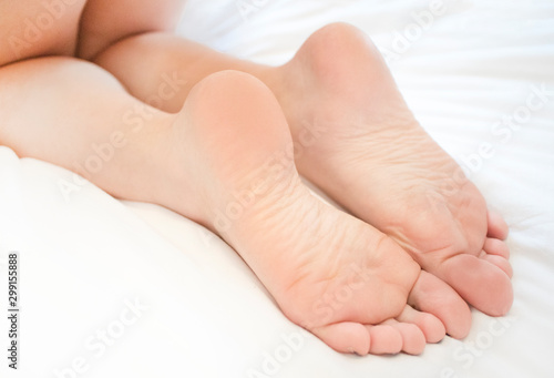 Beautiful Feet Of A Young Woman Kneeling Or Lying In A Bed, Close Up On  White Bedding, Background Healthy, Clean, Well Groomed Female Skin Legs,  Heels Sexy Naked Girl Lying In A
