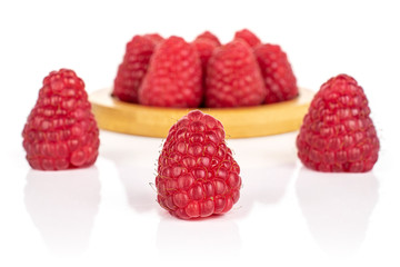 Lot of whole fresh red raspberry on bamboo coaster isolated on white background