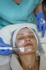 Portrait of middle aged woman having face treatment at beauty clinic