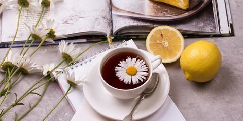 cup of chamomile tea with chamomile flowers and lemon