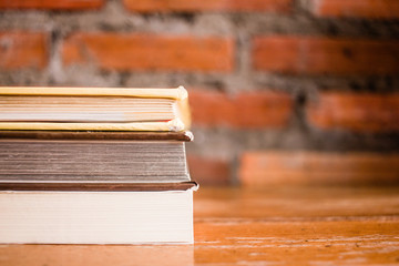 Old books on a wooden shelf with wall brick background