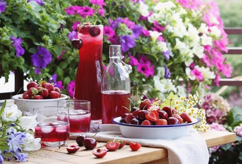 Summer berry cold drink. Iced drink from fresh seasonal berries on bright floral background. © losangela