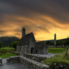 view to the ruins of monastic cemetery of Glendalough, Ireland while sunset , ancient monastery in...