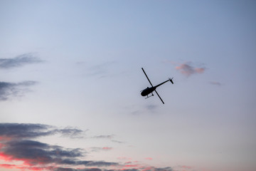 Helicopter against the morning sky, some scattered clouds, emergency mission in progress; aerial vehicle concept.