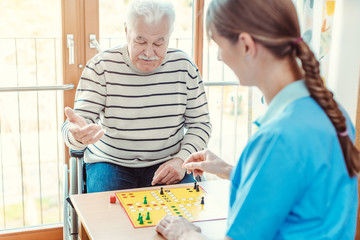 Nurse and senior in retirement home playing a board game