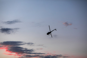 Helicopter against the morning sky, some scattered clouds, emergency mission in progress; aerial...