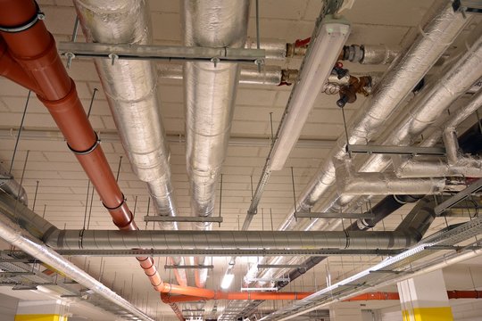 Water pipes and cable trays run under ceiling of a building