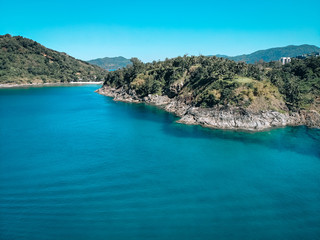 Fototapeta na wymiar Drone view of the lagoon: narrow strip of the white sand, clear blue water and green hills covered with tropical forest; paradise concept.
