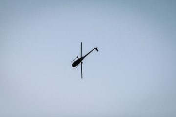 Silhouette of a chopper high in the blue sky seen from below, the military maneuvers; worm’s eye...