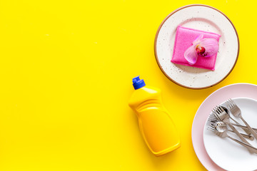 Obraz na płótnie Canvas Dishwashing liquid bottle near plates on yellow background top view copy space