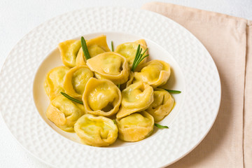 Homemade tortelloni - italian pasta stuffed with ricotta and spinach. Light background.