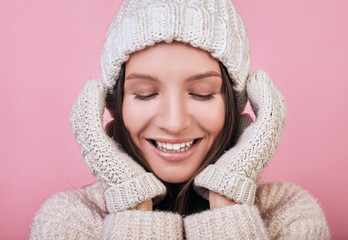 Cute smiling girl with closed eyes in a knitted hat