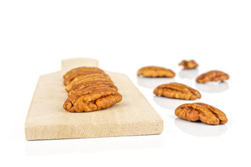 Group of ten whole dry brown pecan nut on small wooden cutting board isolated on white background