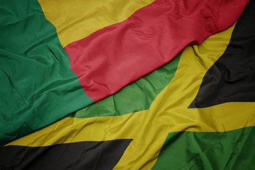 waving colorful flag of jamaica and national flag of benin.