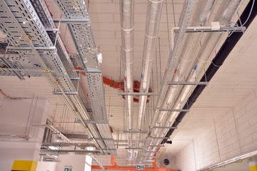 Water pipes and cable trays run under ceiling of a building