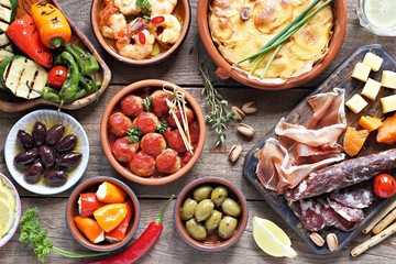 Spanish tapas. Traditional mediterranean appetizer table concept included tortilla, grilled vegetables, meatballs, garlic king prawns,olives and cured meat.