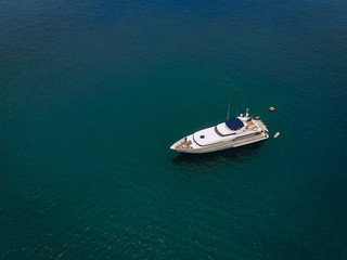 Drone shot of the beautiful white yacht in the warm blue sea; millionaire concept.