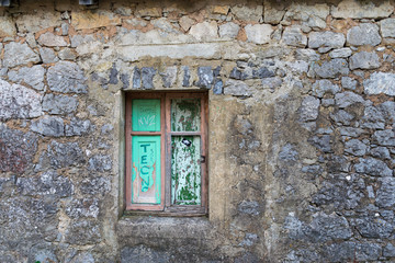 Fototapeta na wymiar Light colored wooden window and green background in stone wall