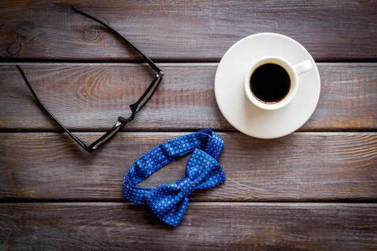 Father's Day or men's birthday concept. Bow tie, glasses and coffee on dark wooden background top view
