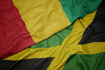 waving colorful flag of jamaica and national flag of guinea.