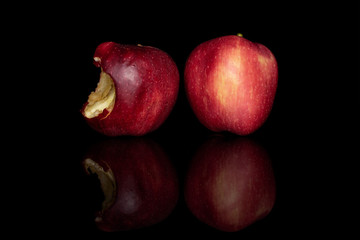 Fototapeta na wymiar Group of one whole and one bitten arranged fresh red apple red delicious isolated on black glass