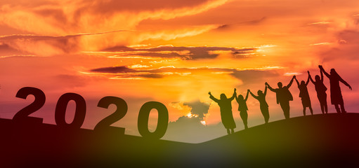 Happy new year 2020, Silhouette of 2020 letters on the mountain with business people raised arms in...