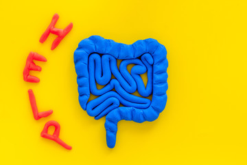 Intestines illness and treatment. Word help near guts on yellow background top view copy space