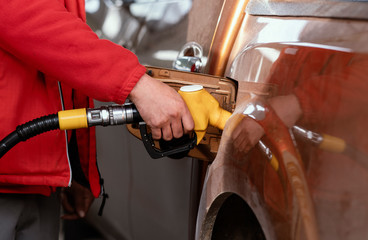 Close up of a hand fueling up a vehicle with a yellow gas pump