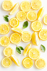 Lemon slices and leaves on white background top view