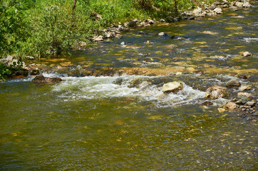 Fototapeta na wymiar Cascade in a shallow mountain river in spring