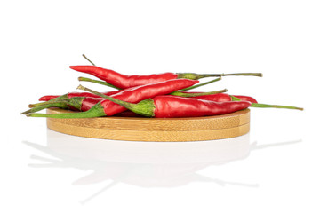 Lot of whole hot red chili on round bamboo coaster isolated on white background