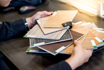 Male architect or interior designer holding wooden color swatch choosing wood material for housing...