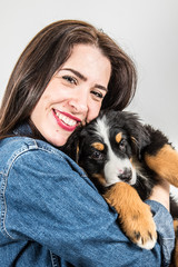 smiling woman hugs puppy from Bernese mountain dog