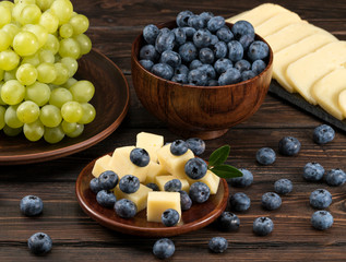 cheese grapes and blueberries on a wooden background