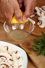 Fototapeta na wymiar Squeezing juice of lemon pulp into small mixing bowl. Making sauce for carpaccio. 