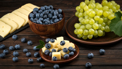 Obraz na płótnie Canvas cheese grapes and blueberries on a wooden background
