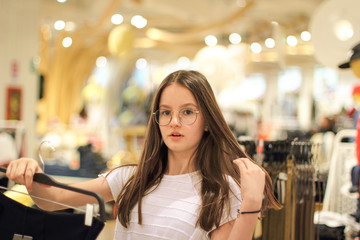 Teen girl choosing clothing at the store. Fashion concept and trends for teenagers.