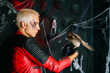 Gothic man with scary bloody makeup and bird of prey on huge scary throne ready for Halloween party