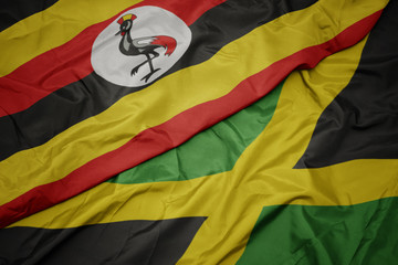 waving colorful flag of jamaica and national flag of uganda.