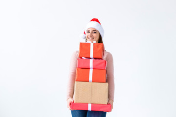 Holidays and people concept - Christmas santa woman shopping holding many gifts wearing santa hat smiling happy on white background with copy space