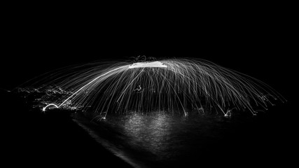 Black and White Semi Circle of Wire Wool Spinning in the Dark on a Lake