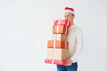 Christmas, holidays and presents concept - man in santa hat holding a lot of gifts on white background with copy space