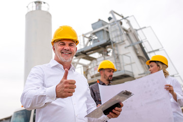 Senior civil engineer showing thumb up, checking project status with ready mix concrete plant and...