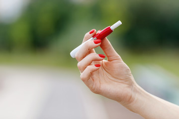 Close-up of hybrid cigarette in female hands. Tobacco heating system or new electronic cigarettes.