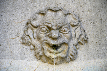 a stone face in an old fountain