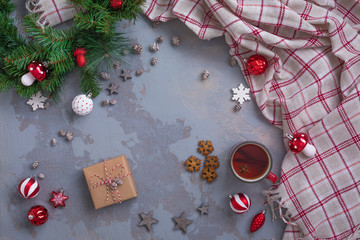 Christmas tea cup with cinnamon, cookies, Fir Tree Branches, toys, presents, plaid on concrete linen background