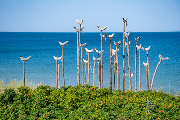 Wooden sculpture of a group of seagulls with blue sea and sandy beach in the background