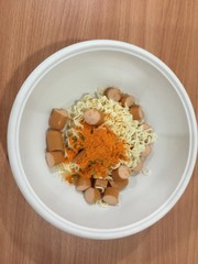 Pieces of noodles and hot dogs in a wooden floor cup