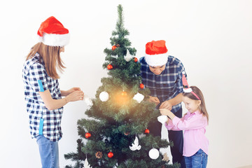 Holidays, parents and celebrating concept - Happy family decorating a Christmas tree with baubles in the living-room on white background